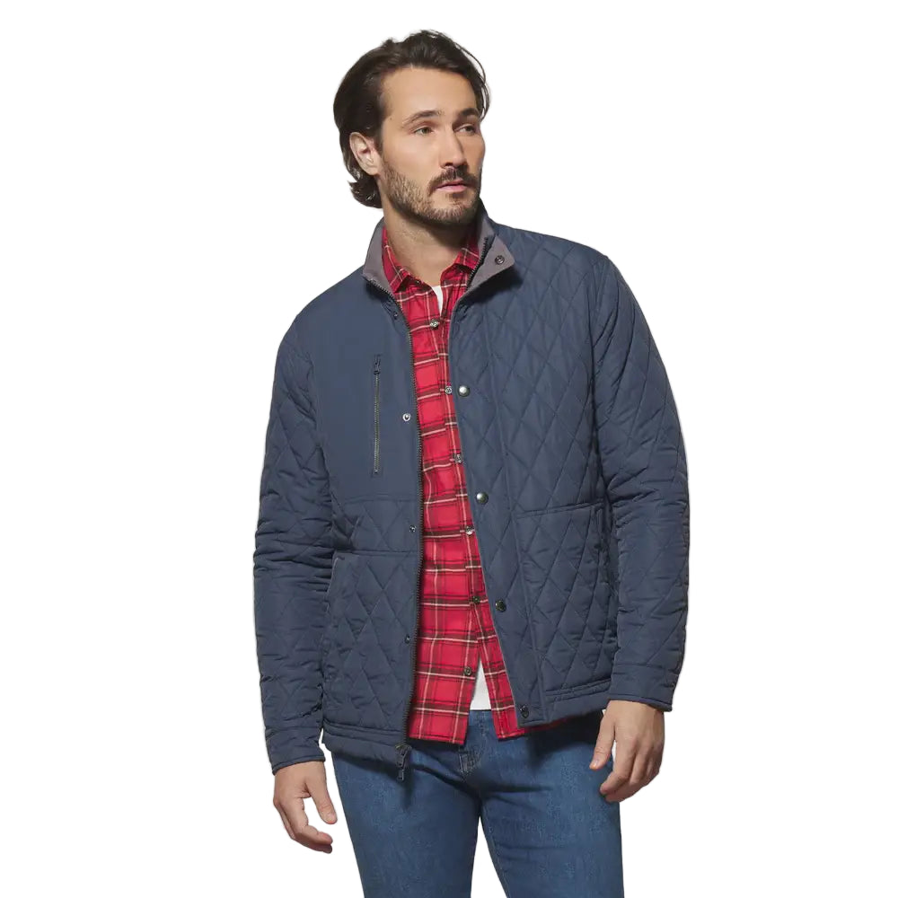 Man wearing a blue quilted jacket over a red plaid shirt on a white background